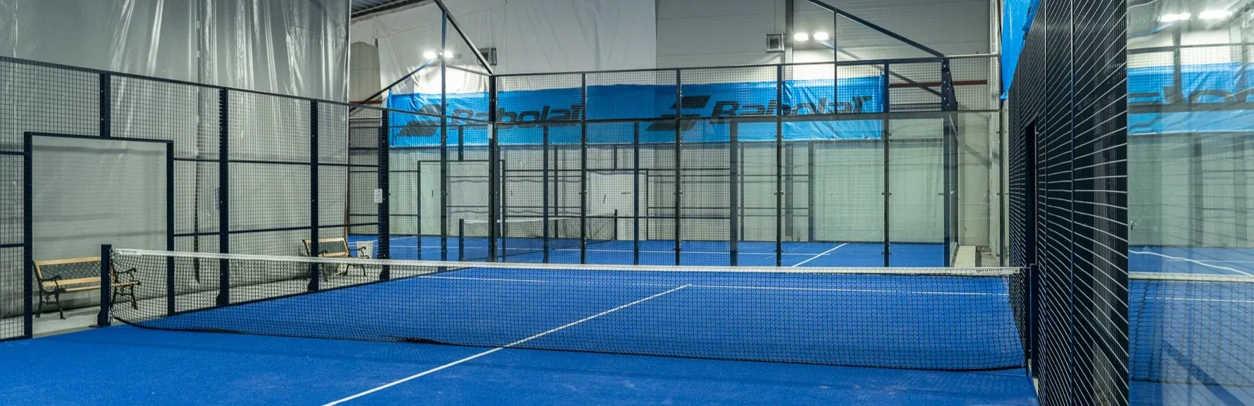 Innendørs padelbaner med blått dekke og høy takhøyde